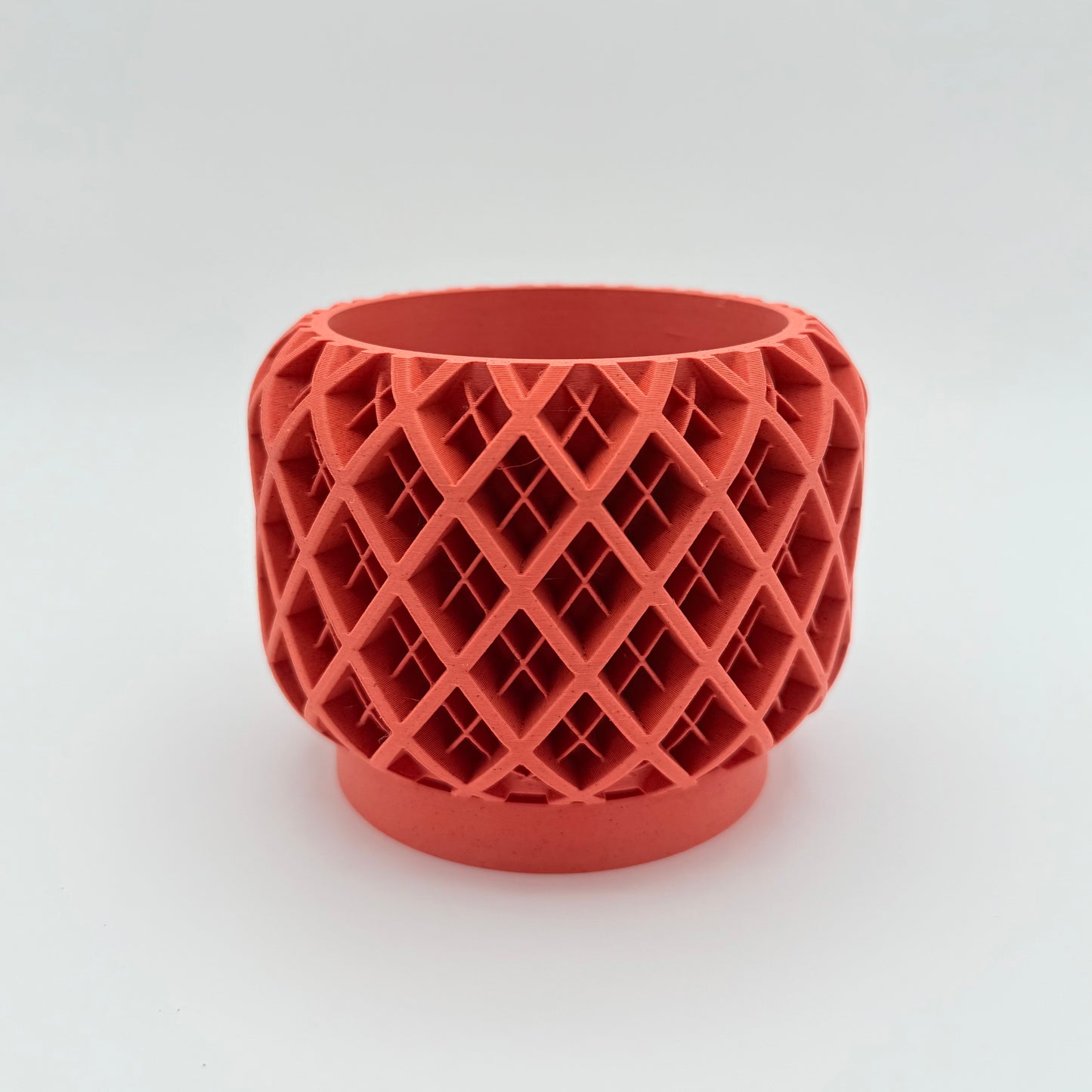 GeoPlaid 3D printed planter with a geometric plaid pattern and a drainage tray. Shown in terracotta.