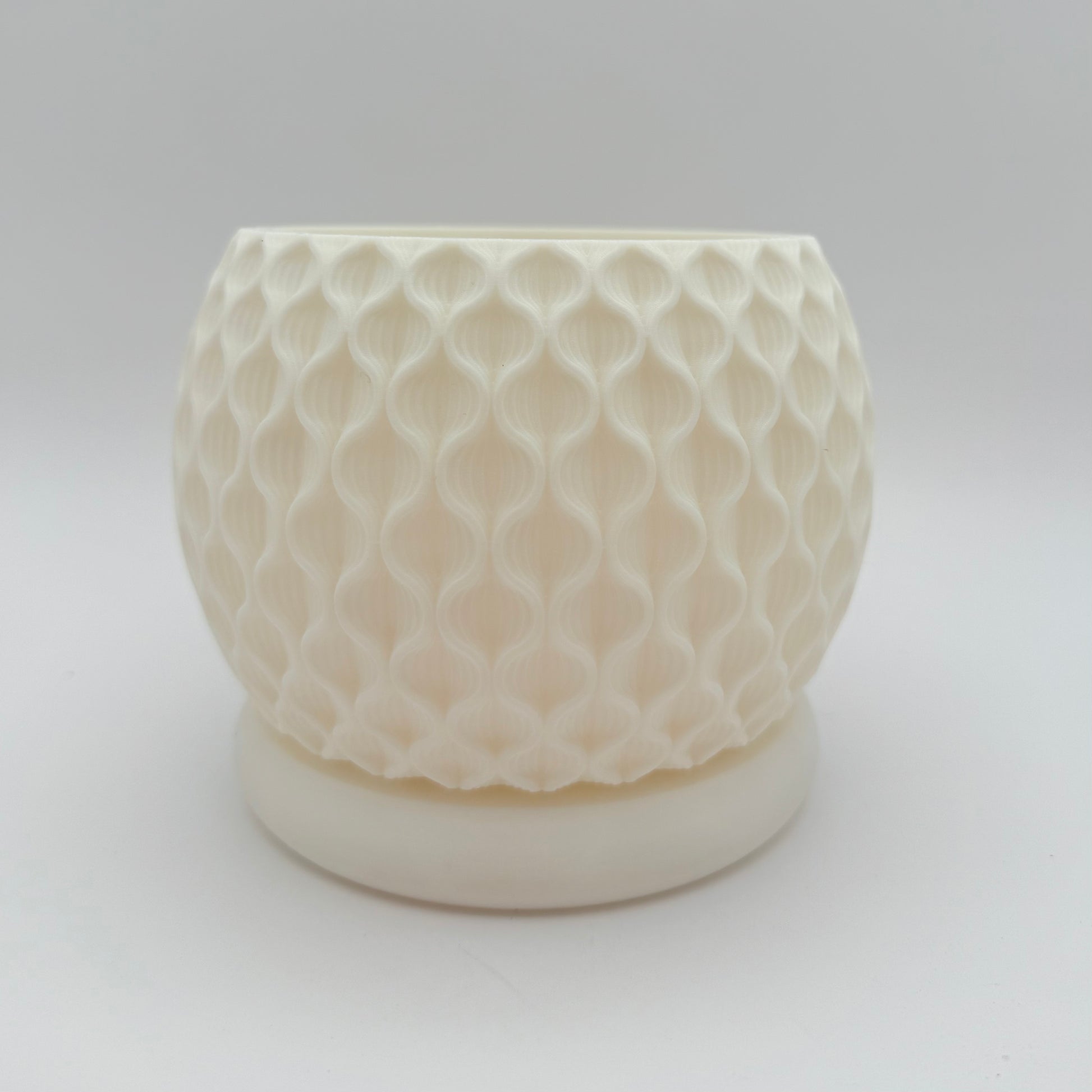 This 3D printed Lotus Planter with drainage tray has an intricate, flower-like pattern. Shown in white pearl.