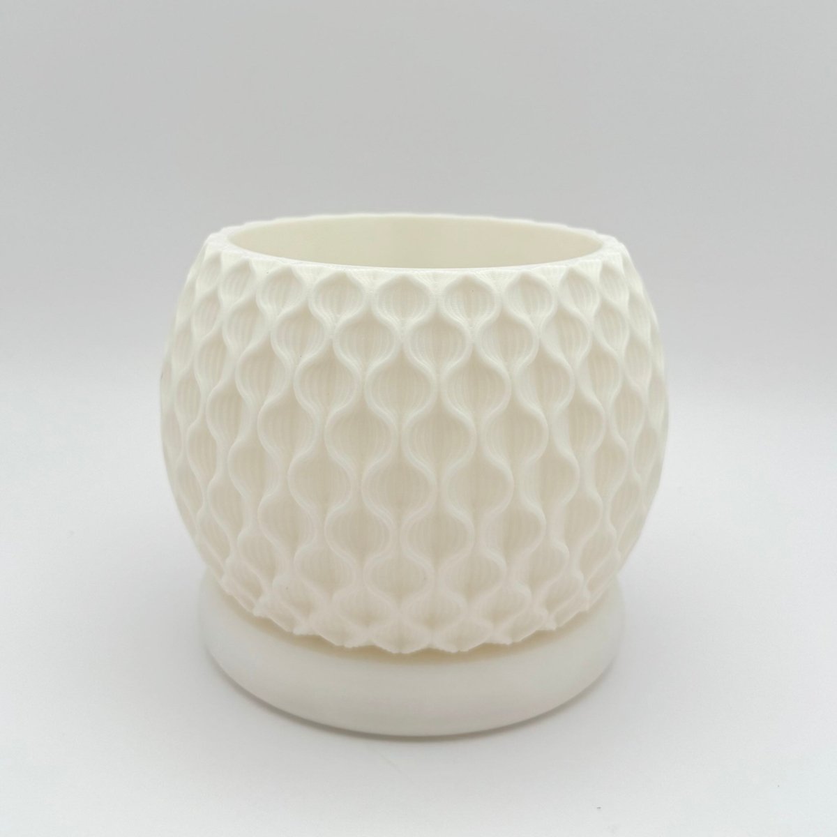 Round lotus indoor planter pot with a textured, raised wavy floral pattern on its exterior and a smooth, matching tray underneath